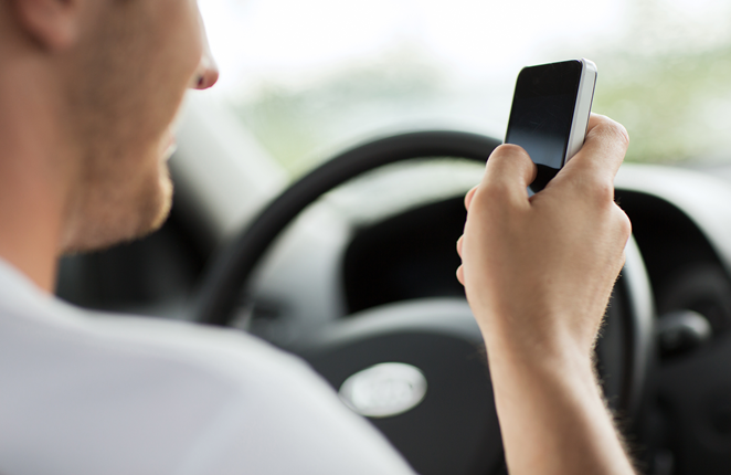 A man checking his phone while driving.